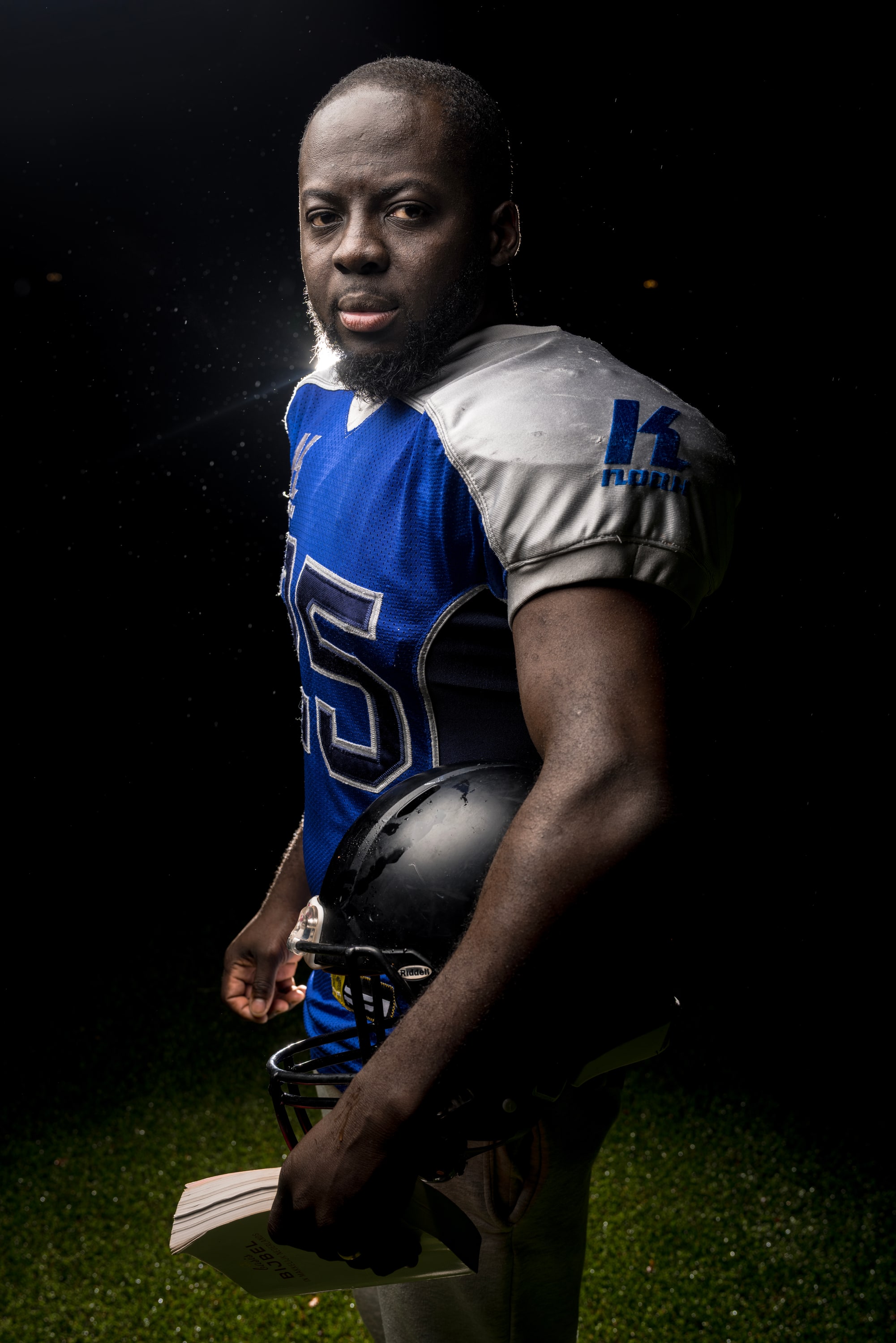 Godwin Arhin in american football tenue met een helm en een Bijbel onder zijn arm