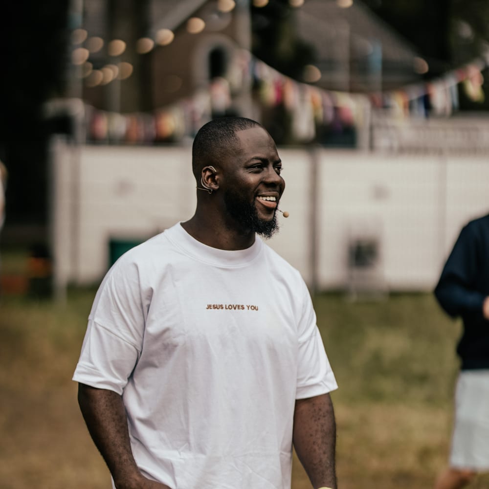 Godwin Arhin spreekt met een headsetmicrofoon tijdens een evenement in de buitenlucht